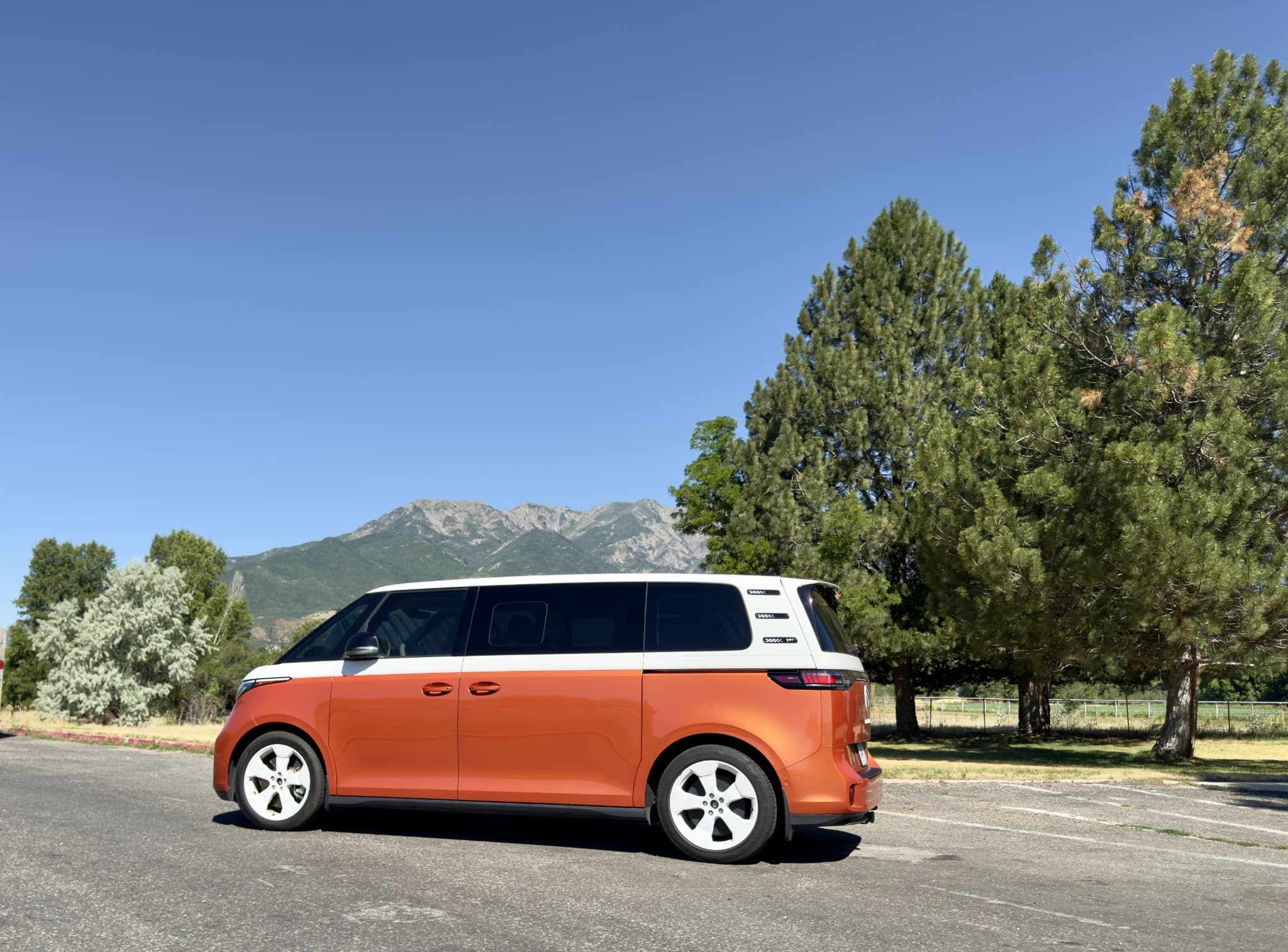 Trusted Treks' orange-and-white Volkswagen ID. Buzz with Pikes Peak in the background